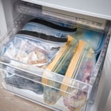 Fryslåda med plastpåsar som innehåller frysta livsmedel, som visar återanvändbar förvaring.
