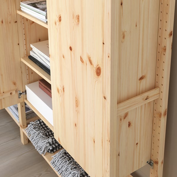 Förvaringsmöbel i trä med flera hyllor delvis fyllda med böcker. Den modulära designen gör det möjligt att justera hyllavståndet.