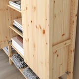 Förvaringsmöbel i trä med flera hyllor delvis fyllda med böcker. Den modulära designen gör det möjligt att justera hyllavståndet.