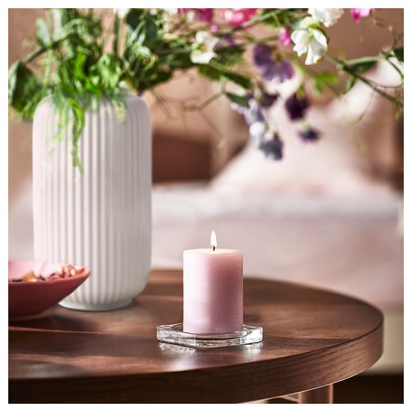 Ett mysigt rum med ett JÄMNMOD doftljus och blommor.