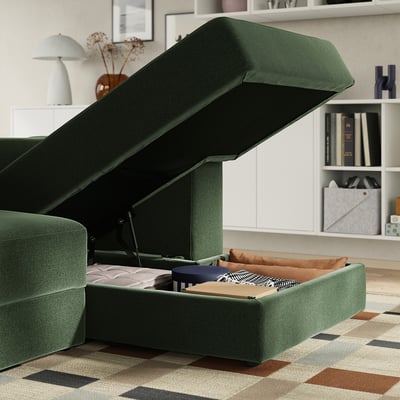 Grön L-formad soffa med upphöjd sittplats som avslöjar förvaring och dynor.