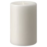 Detta är ett vitt, cylindriskt JUBLA-ljus med en slät yta, tillverkat av stearin, som står upprätt med en veke i toppen.