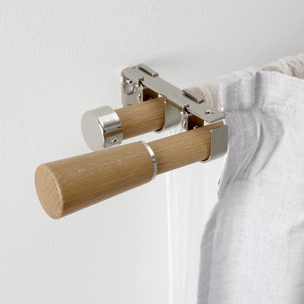 En modern gardinstång i trä med metallfästen monterade på en vägg, som visar upp elegant design och robust montering.