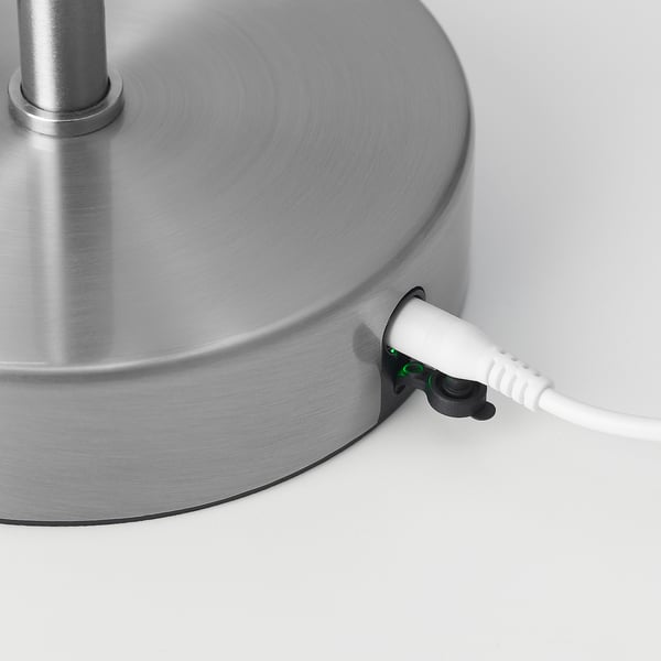 Lampfot i silverfärgad metall med en nätsladd ansluten till den.