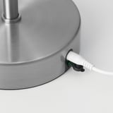 Lampfot i silverfärgad metall med en nätsladd ansluten till den.