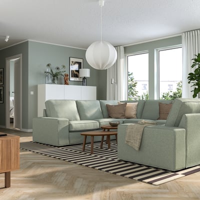 Modernt vardagsrum: ljusgrön l-soffa KIVIK med soffbord i trä, randig matta, vit taklampa och stora fönster med gardiner.