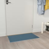 Blårutig dörrmatta med namnet KLAMPENBORG passar under vit dörr, liten skohylla till höger, ljust trägolv.