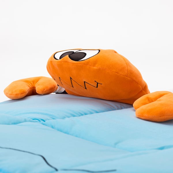 Uppstoppad orange krabbleksak med stora ögon på blått tyg. Ser mjuk ut, av hög kvalitet.