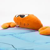 Uppstoppad orange krabbleksak med stora ögon på blått tyg. Ser mjuk ut, av hög kvalitet.