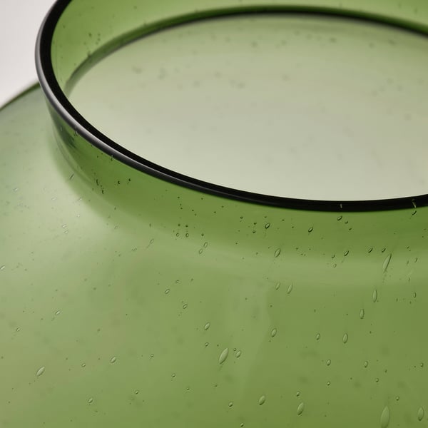 Grön glasvas med vattendroppar, som visar slät struktur och handgjord kvalitet.