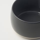 Kruka i mörkt stengods med slät, blank yta. Rundad kant och robust bas.