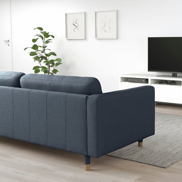 Blå soffa med avtagbara armstöd, tv, konst, grön växt.