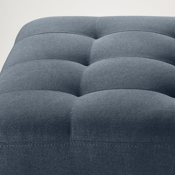 Fotpall i grått tyg med fasta dynor för komfort och stöd. Modern, stilren design med tight tygpassform och snygga sömmar.