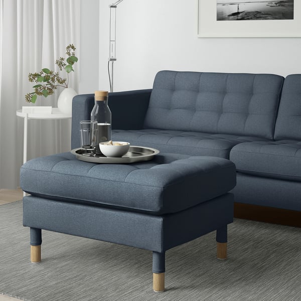 Blå soffa med matchande fotpall, används som extra sittplats eller förlängning. Inkluderar bricka med glas och skål.