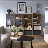 Modernt vardagsrum med bokhylla i trä, fåtöljer, soffbord.