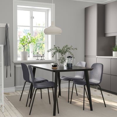 Modern matgrupp med svart rektangulärt bord LISABO, fyra grå stolar, gråaktig taklampa, krukväxter och ett fönster.
