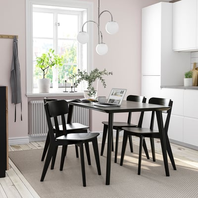 Svart LISABO matbord och stolar, modernt minimalistisk design, passar snyggt i små utrymmen, ljusa trägolv och rosa väggar.