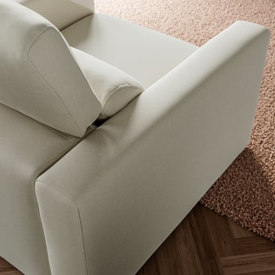 Föreställer en beige MALMKÖPING-fåtölj på en texturerad matta. Fåtöljen har rena linjer och mjuka, stödjande dynor, som utstrålar både stil och komfort.