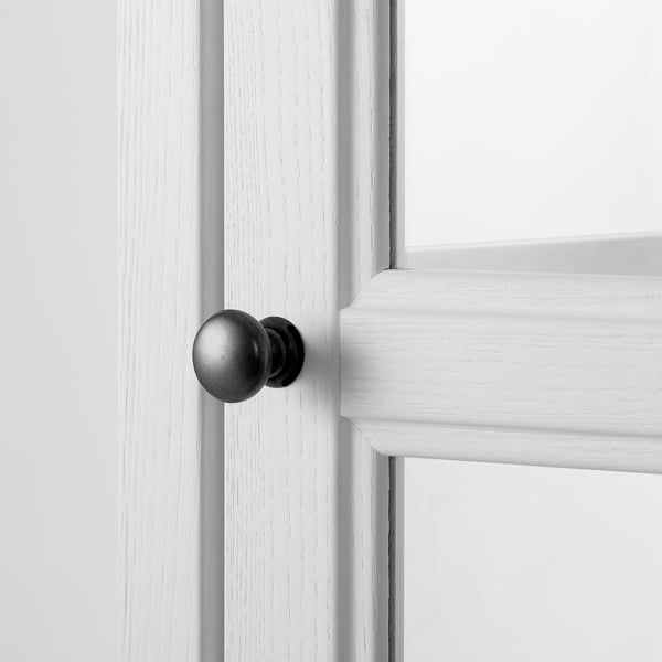 Närbild av vitt skåphandtag på polerad dörrkant. Slät finish, elegant design och exakt montering.