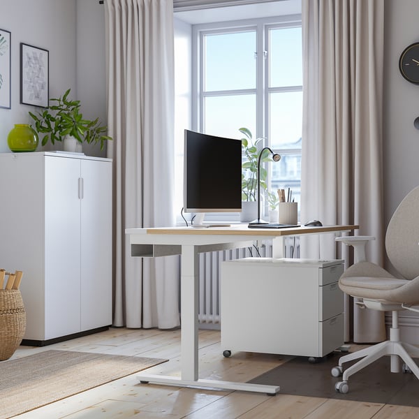 Modernt hemmakontor med höj- och sänkbart skrivbord, skärm, stol och naturligt ljus från MITTZON.