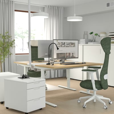 Modern kontorsinredning med höj- och sänkbart skrivbord MITTZON, grön ergonomisk grönfjällsstol, skärm och vit förvaringsmöbel.