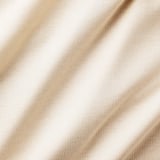 Närbild av beige gardintyg med subtil textur som visar upp dess kvalitetsväv och mjuka utseende.