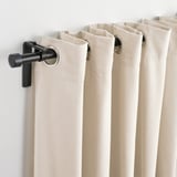 Ljusfiltrerande gardiner med moderna ringar som erbjuder avskildhet och ljuskontroll på ett elegant sätt.