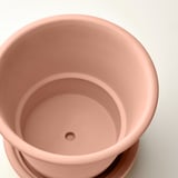 Närbild av rosa krukor interiör med dräneringshål, som visar slät struktur och kvalitet.