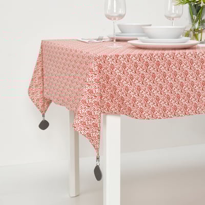 Röd duk med vitt blommönster fäst med svarta klämmor på ett matbord, redo för en måltid.