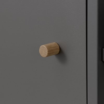 Ett modernt, minimalistiskt skåp med en mattgrå finish och ett cylindriskt trähandtag som visar upp kvalitetsdesign och hantverk.