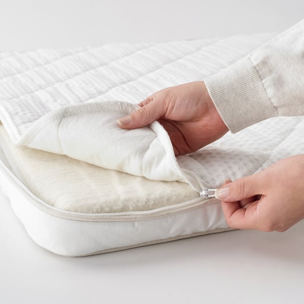 Person som öppnar vit bäddmadrass med naturlatex, som visar avtagbart överdrag.