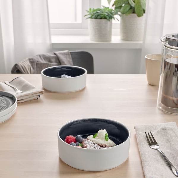 Matbord med skålar med glass, bär och is; servetter, bestick, växter.