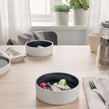 Matbord med skålar med glass, bär och is; servetter, bestick, växter.