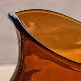 Kanna i bärnstensfärgat glas, munblåst med intrikata mönster, som visar upp fint hantverk.