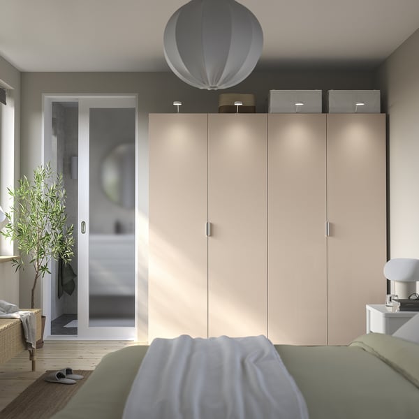 Modernt sovrum med stor PAX-garderob, gröna sängkläder och rund taklampa.