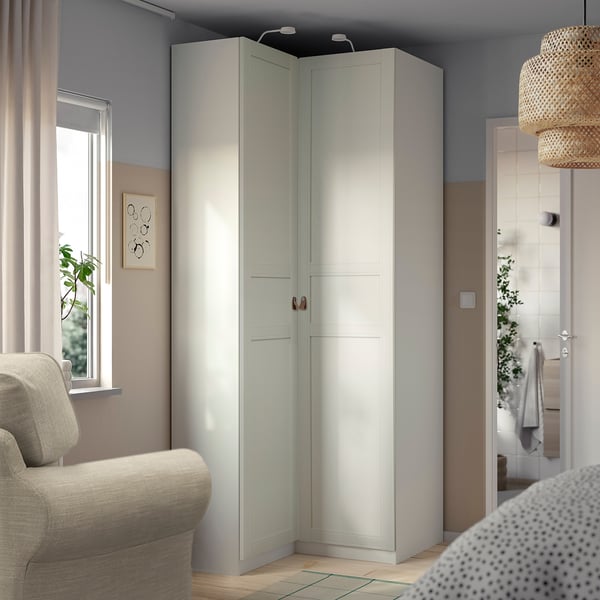 Vit IKEA PAX hörngarderob i rummets hörn, matchande minimalistisk inredning.