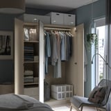 En öppen beige PAX-garderob med kläder och förvaringslådor, upplyst med innerbelysning.