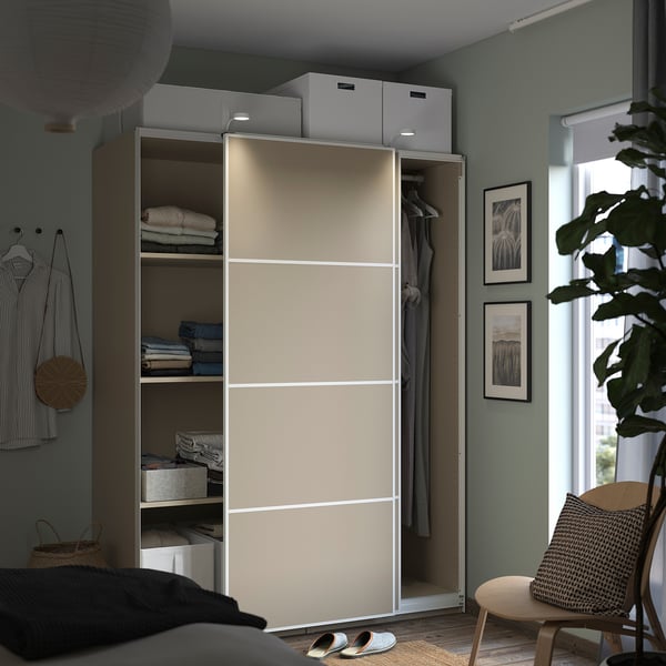 Modernt sovrum med beige PAX-garderob, med hyllor, kläder och dekorationer.