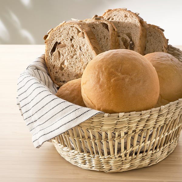En flätad korg med bröd, med en randig duk inuti.