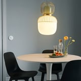 Modern matplats med guldupphängd lampa, bord och inredning.