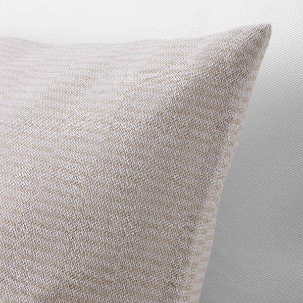 Närbild av ett beige kuddfodral med subtil randig textur som visar upp mjuk, vävd bomullskvalitet.