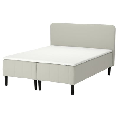 Sängen RÅHOLMAR : klädd i ljusbeige, rektangulär med vadderad sänggavel.