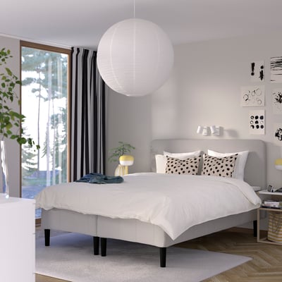 Minimalistiskt sovrum: vit säng, grå sänggavel, svarta accenter, växter, gul lampa. Antal: 48 tecken