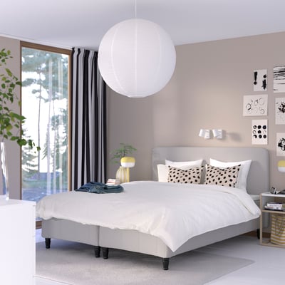 Modernt minimalistiskt sovrum med sängen RÅHOLMAR , lila vägg, lykta, gardiner och färgade accenter.