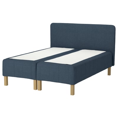 Modern blå säng med vadderad sänggavel, träben, lugn design.