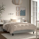 Beige & vit säng RENFJÄLLET med randigt täcke, mjuk taklampa, minimalistisk inredning.