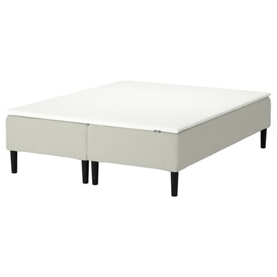 Vit klädd plattformssäng med träben, modern minimalistisk design.