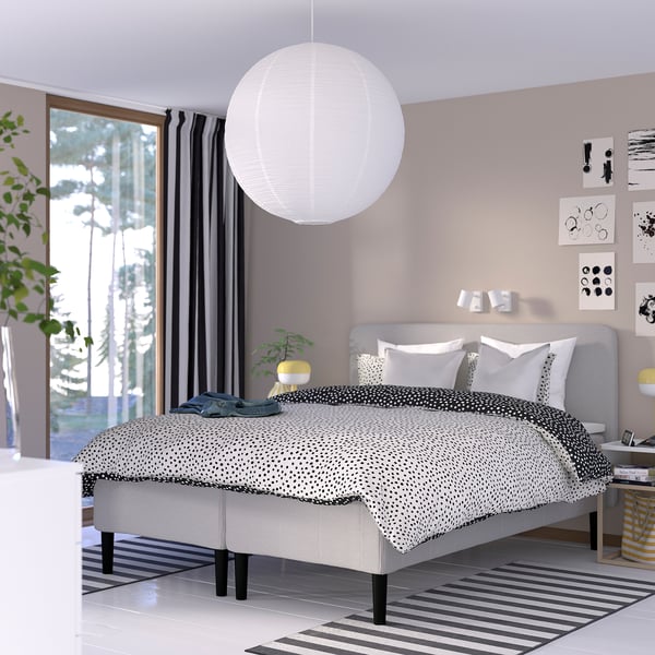 Modernt sovrum med sängen RISEHÖJDEN , prickiga sängkläder, taklampa och mörkläggningsgardiner. Minimalistisk inredning, mysig atmosfär.