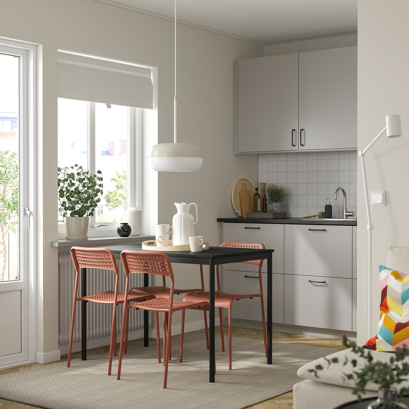 Modernt kök med orange, stapelbara Sandberg-stolar nära grå skåp och stora fönster.