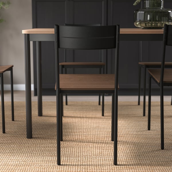 Modern stol med svarta metallben och träsits. Designad för komfort och små utrymmen.